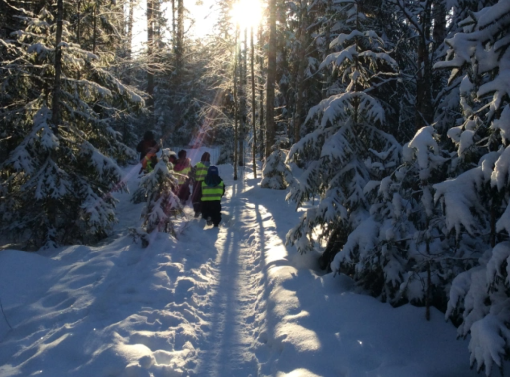 Lapset kävelevät lumisessa metsässä