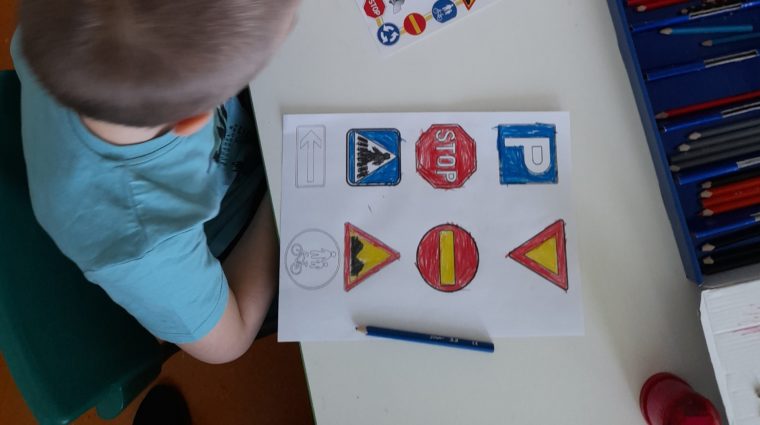 Poika värittää liikennemerkkejä.