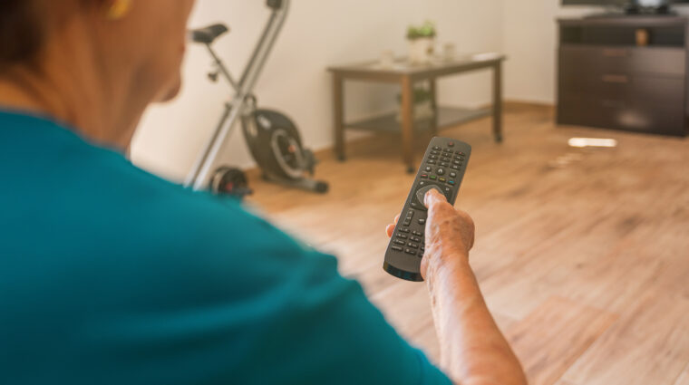 iäkkäämpi nainen katsoo televisiota kaukosäädin kädessään