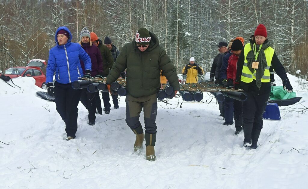 Talkoolaiset kantavat lintujen pesimälautan runkoa järvelle Isiäisellä