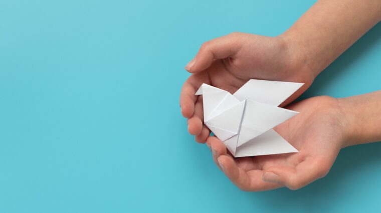 Valkoinen origamikyyhkynen lapsen käsissä
