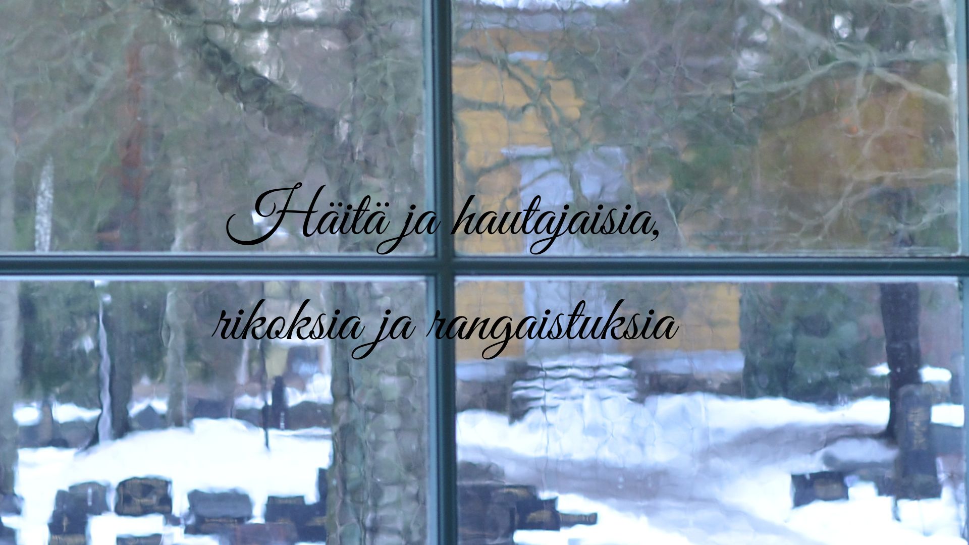 Sumean neliruutuisen lasi-ikkunan takaa näkyy talvinen hautausmaa mustine hautakivineen. Taustalla on keltainen kellotapuli ja lähinnä ikkunaa näkyy koivun runko.