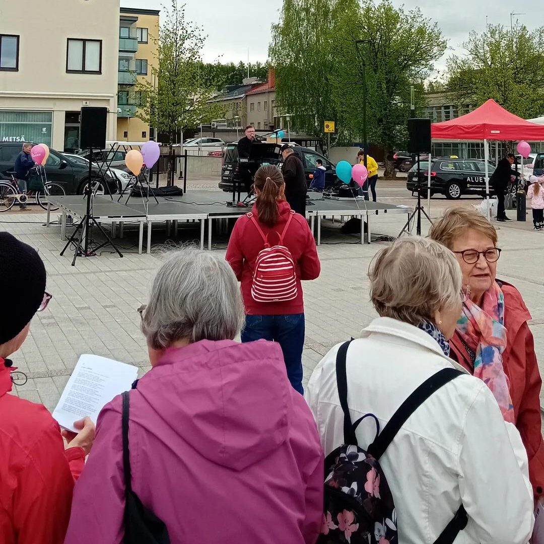 Pianisti Jari Puhakka soittaa lavalla pianoa. Yleisö laulaa yhdessä lauluja yhteislauluvihkoista.