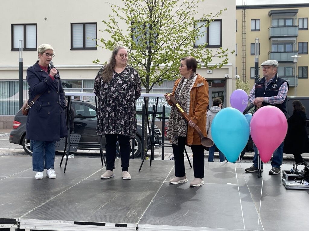 Yhteisöllisyyden kauha -palkintoa pitää kädessään Heinolan Eläkkeensaajat ry:n edustaja. Kuvassa toisena vasemmalta katsottuna seisoo Henna Paasonen, joka on juuri ojentanut palkinnon voittajalle. Heinolan kaupungin hyvinvointijohtaja Pirjo Hepo-oja seisoo kuvassa vasemmalla reunalla ja juontaa palkinnonjakoa.