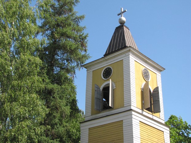 Heinolan kirkon kellotapuli kohoaa sinistä taivasta vasten. Kelloluukut on avattu.