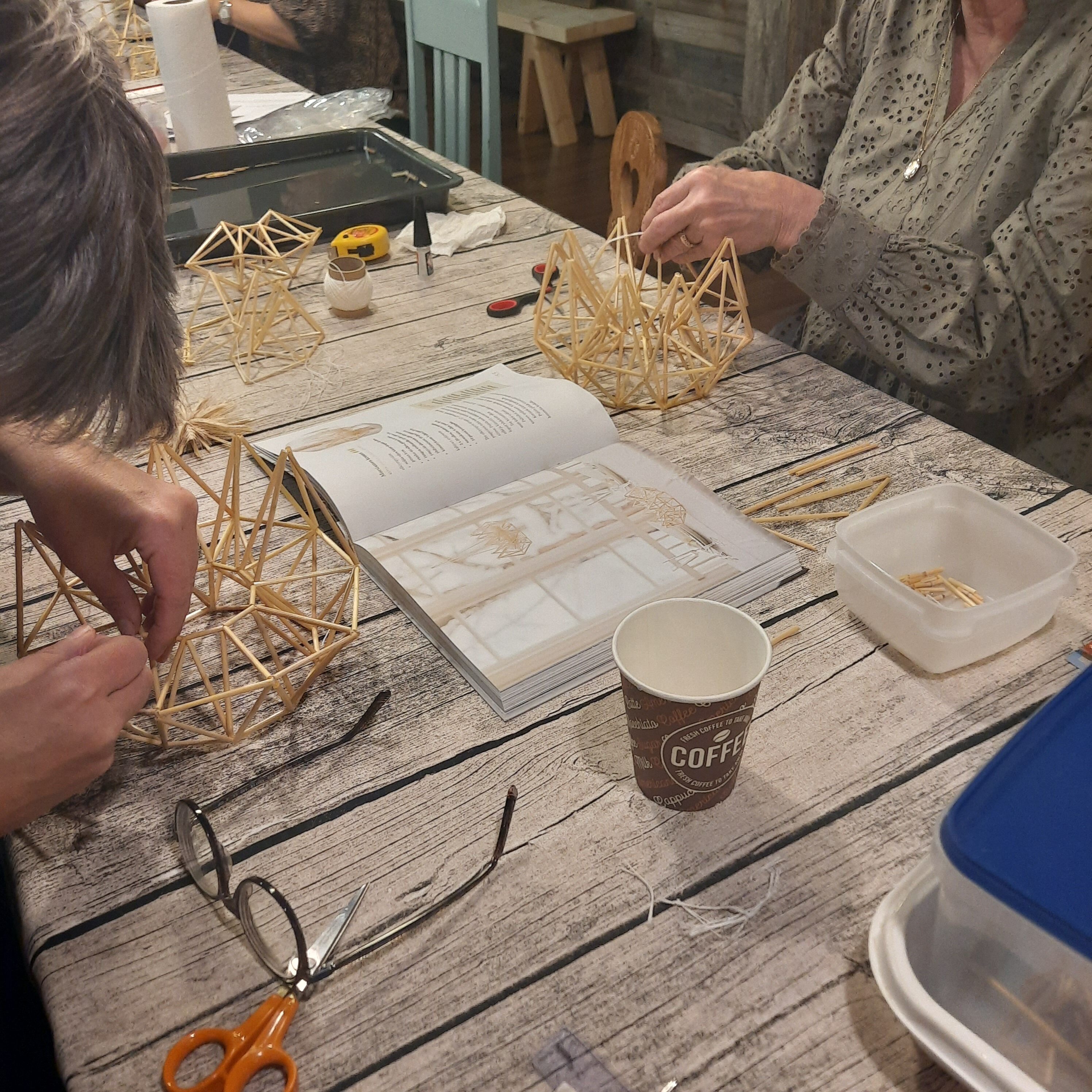 Pöydän ääressä valmistetaan himmeleitä rukiinoljista.