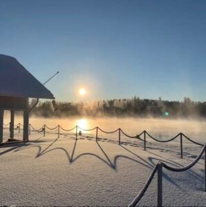 Aurinkoinen ja talvinen kuva Heinolan satamasta joelle päin. Kuvassa mukanahieman Tyyrpuurin katosta ja aitaa.