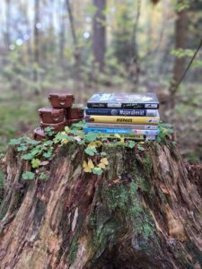 Kirjoja ja geokätköpurkkeja kannon päällä metsässä.