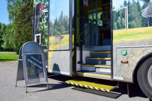 Kirjastoauton ovi avoinna oven vieressä mainosständi jossa teksti tervetuloa kirjastoautoon.